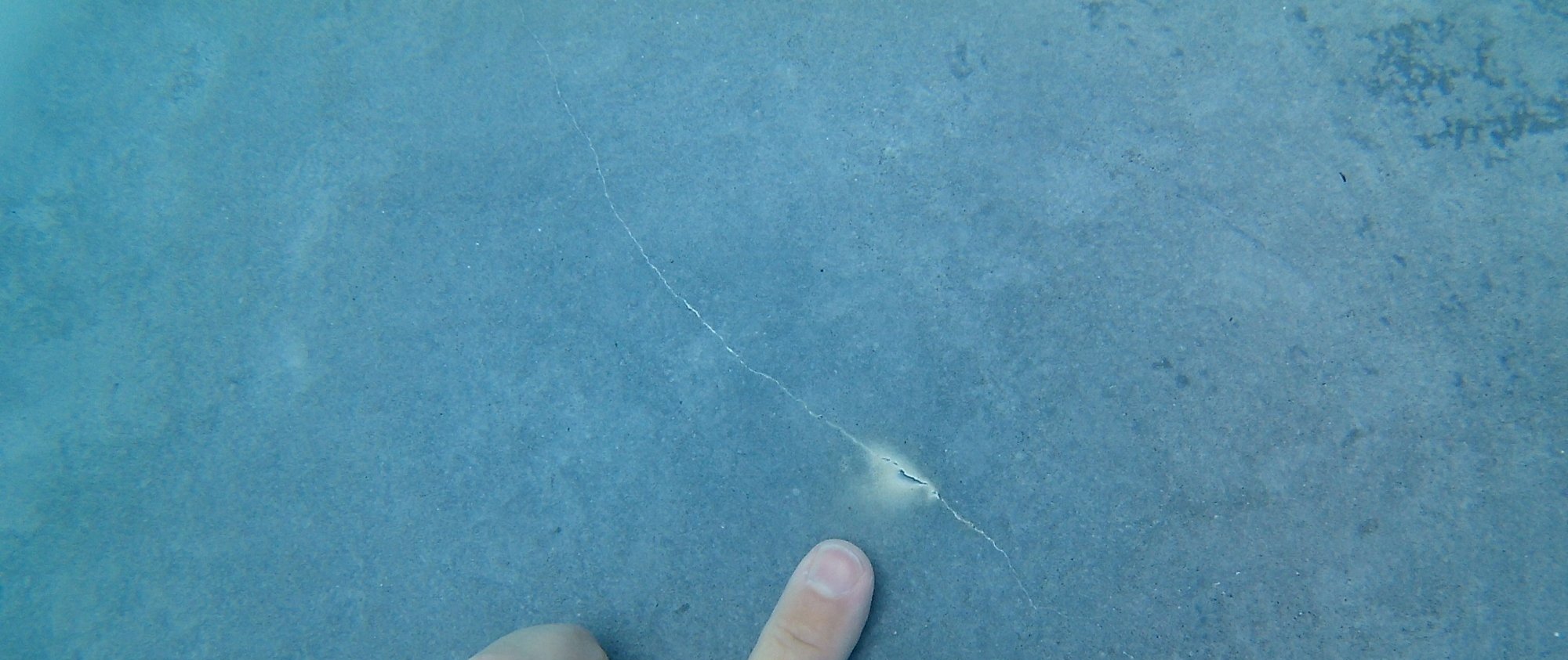 Calcium leach damage on a pool surface, showing a visible streak where calcium has been pulled from the plaster.